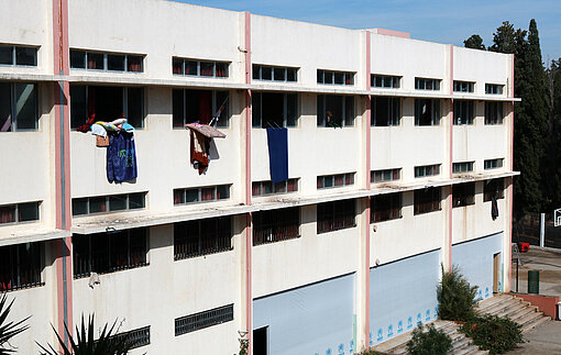Ein Schulgebäude, bei dem aus einigen Fenstern Wäsche zum Trocknen hängt