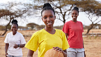 Drei junge Frauen draußen mit einem Basketball
