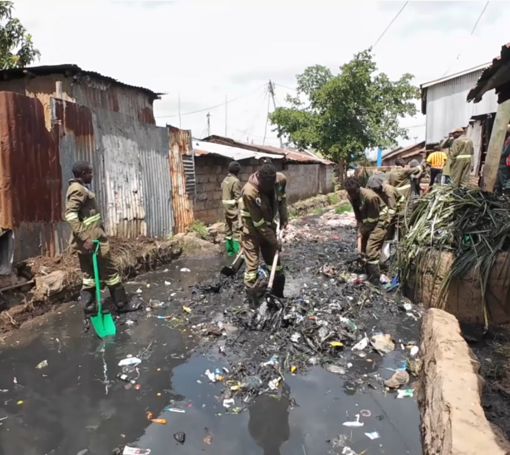 Das Team von „Slums Going Green“ säubert einen mit Abwasser und Müll vollgelaufenen Graben vor einigen Hütten