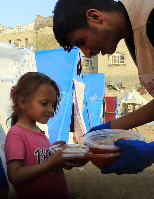 Ein Helfer verteilt Speisen an Kinder