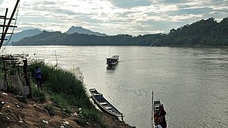 Menschen und Fähren am Mekong